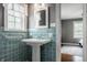 This bathroom features a pedestal sink, bright turquoise tile and updated fixtures at 5800 Lawrence Dr, Indianapolis, IN 46226