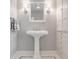 This bathroom features a pedestal sink, updated fixtures, and bright lighting and classic tile at 5800 Lawrence Dr, Indianapolis, IN 46226
