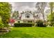 Manicured backyard with lush greenery and a beautifully designed brick and white home at 5800 Lawrence Dr, Indianapolis, IN 46226