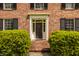 Classic brick home featuring a welcoming front door framed by manicured bushes and symmetrical windows at 5800 Lawrence Dr, Indianapolis, IN 46226