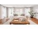 Bright living room featuring hardwood floors, a white sofa, and multiple windows with white curtains at 5800 Lawrence Dr, Indianapolis, IN 46226