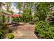 Brick patio with outdoor dining set, complemented by lush landscaping and mature trees at 5800 Lawrence Dr, Indianapolis, IN 46226