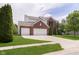 Attractive two-story brick home featuring a well-kept lawn, mature tree, and a convenient attached two-car garage at 6839 Powder Dr, Indianapolis, IN 46259
