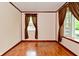 Empty bedroom with hardwood floors, neutral walls, and two windows with brown curtains at 7228 Kimberly Ln, Plainfield, IN 46168
