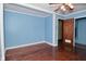 Bedroom featuring blue walls, wood trim, hardwood floors, and a ceiling fan at 7228 Kimberly Ln, Plainfield, IN 46168