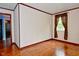 Empty bedroom with hardwood floors, neutral walls, and a window with brown curtains at 7228 Kimberly Ln, Plainfield, IN 46168