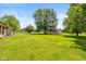 Large backyard featuring shed, mature trees, and manicured lawn, perfect for outdoor activities and recreation at 8111 Timberwood Dr, Plainfield, IN 46168