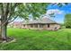 Lush green backyard with mature trees, providing shade and a serene atmosphere, complemented by the home's brick facade at 815 Stewart Rd, Anderson, IN 46012