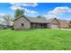 Inviting one-story brick home showcasing a lush green lawn and a covered front porch at 815 Stewart Rd, Anderson, IN 46012