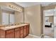 Bathroom with a double vanity, illuminated mirror, and open doorway leading to a bedroom at 8704 New Heritage Dr, Indianapolis, IN 46239