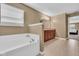 This bathroom has a white tub next to the double vanity and a view of the bedroom at 8704 New Heritage Dr, Indianapolis, IN 46239