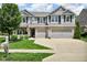 Two-story house featuring a well-manicured lawn and garden, three-car garage and neutral exteriors at 8704 New Heritage Dr, Indianapolis, IN 46239