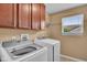 Laundry room showcasing a side-by-side washer and dryer, storage cabinets and a window at 8704 New Heritage Dr, Indianapolis, IN 46239
