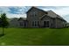 Large backyard featuring lush green grass, mature tree, and an outdoor dining set on a patio at 8732 Wicklow Way, Brownsburg, IN 46112