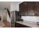 View of the kitchen featuring stainless steel refrigerator and dark wood cabinets, with stairs visible in the background at 8732 Wicklow Way, Brownsburg, IN 46112