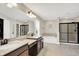 Bathroom with double vanity, neutral tile, tub, and glass shower enclosure at 9179 Brookstone Pl, Zionsville, IN 46077