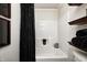 Clean bathroom featuring a shower-tub combo, custom shelves, and elegant black accents at 9324 W Point Pl, Indianapolis, IN 46268