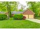 Charming brick home featuring a two-car garage and a lush green lawn surrounded by mature trees at 9324 W Point Pl, Indianapolis, IN 46268