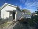 Outside view of detached garage with door ajar on a sunny day with a gravel driveway and chain link fence at 1122 Shelby St, Shelbyville, IN 46176