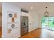 Bright kitchen features stainless steel refrigerator, open shelving, hardwood floors, and a sliding glass door to the backyard at 12290 Charing Cross Rd, Carmel, IN 46033