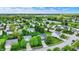 Scenic aerial view of a neighborhood with diverse home styles, lush greenery, and a tranquil pond in the distance at 13209 Westwood Ln, Fishers, IN 46038