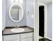 Powder room featuring gray walls, white vanity with gray countertop, a round mirror, and an open door at 13209 Westwood Ln, Fishers, IN 46038