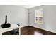 Office area featuring dark hardwood floors, gray walls, a black floor lamp, and a window with blinds at 13209 Westwood Ln, Fishers, IN 46038