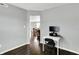Office space with dark hardwood floors, gray walls, a white desk, and views into the dining and living spaces at 13209 Westwood Ln, Fishers, IN 46038