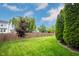 Sprawling backyard boasts a green lawn, a wood fence, mature trees, and a home in the distance under a partly cloudy sky at 14030 Avalon East Dr, Fishers, IN 46037