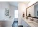 Bright bathroom boasts double sinks with white cabinets and a large soaking tub next to a window at 14030 Avalon East Dr, Fishers, IN 46037