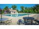 Outdoor community pool with lounge chairs, tables, a pool house, and trees under a clear blue sky at 14030 Avalon East Dr, Fishers, IN 46037