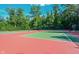 View of the community tennis court with red and green surface and surrounded by trees at 14030 Avalon East Dr, Fishers, IN 46037