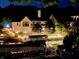 Night view of home from the lake featuring a lighted boat dock, beautiful landscaping, and architectural details at 14035 Stone Key Way, Fishers, IN 46037