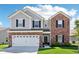 Charming two-story home with a brick and vinyl exterior, attached garage, and well-manicured lawn at 1452 Bigleaf Dr, Sheridan, IN 46069