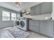 Well-lit laundry room with gray cabinets, wooden countertops, modern washer and dryer, and wood-look tile flooring at 1476 Anon Ct, Greenwood, IN 46143