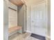 Mudroom with built-in bench, coat hooks, storage cabinets, wood plank accent wall, and tiled flooring at 1476 Anon Ct, Greenwood, IN 46143