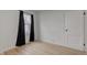 Bedroom featuring wood-look floors, one window with dark curtains, and a white door at 1517 Wallace Ave, Indianapolis, IN 46201