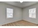 Bedroom featuring wood-look floors, two windows with blinds, and white walls at 1517 Wallace Ave, Indianapolis, IN 46201