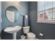 Stylish powder room with a pedestal sink, round mirror, and a blue accent wall that adds a touch of modern elegance at 15369 Mystic Rock Dr, Carmel, IN 46033