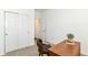 Bright bedroom featuring neutral carpet, white walls, closet with bi-fold doors, and a wooden desk with plants at 1829 James Pierce Dr, Shelbyville, IN 46176