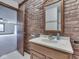 Rustic bathroom featuring brick accents, a wooden-framed mirror, and stylish vanity at 31 N Restin Rd, Greenwood, IN 46142