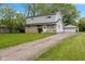 Two-story home featuring stone accents, light gray siding, a detached garage, and a paved driveway at 3425 N Elizabeth St, Indianapolis, IN 46226
