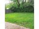 View of the backyard with mature trees and an ample green space with a wooden fence for privacy at 3453 Payton Ave, Indianapolis, IN 46226