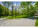 Lush green grounds with mature trees and a gravel driveway at 3660 S Conservation Club Rd, Morgantown, IN 46160
