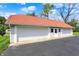 View of a three car garage with white siding, a red tile roof and an asphalt driveway on a sunny day at 3744 S Meridian St, Indianapolis, IN 46217