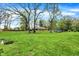 Sprawling backyard with mature trees and a distant view of the house and two parked cars at 3975 Denwood Dr, Indianapolis, IN 46226