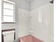 Bathroom featuring pink tub, pink tiled ledge, vinyl shower surround and a window at 3975 Denwood Dr, Indianapolis, IN 46226
