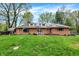 Charming brick home featuring solar panels, a well-maintained lawn, and mature trees, all under a bright blue sky at 3975 Denwood Dr, Indianapolis, IN 46226