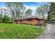 Inviting red brick house with solar panels, a driveway, and mature trees creating a serene and private setting at 3975 Denwood Dr, Indianapolis, IN 46226