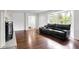 Spacious living room with gleaming hardwood floors, a black leather sofa, and a decorative fireplace at 3975 Denwood Dr, Indianapolis, IN 46226